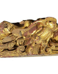 Gold and red wood temple carving with bird among swirling clouds, intricate detailing, close-up view.