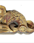 Close-up of gold and red antique Chinese temple carving with ornate swirling, scale-like traditional patterns.