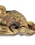 Close-up of gold and red antique Chinese temple carving with ornate swirling, scale-like traditional patterns.