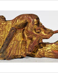 Close-up of gold and red wood griffin carving with intricate wings and lion-like face from antique Chinese temple.