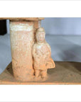 Brown terracotta town gate with small figure and cylindrical column, 17th century Chinese, museum display setting.