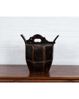 Brown wooden Chinese wedding box with carved handle, animal and foliage motifs on a wooden table against white brick wall.