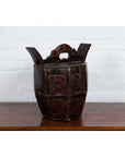 Brown wooden antique box with carved handle, animal and foliage motifs, on a wooden table indoors.