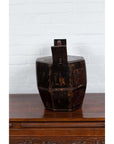 Brown wooden Chinese wedding box with carved handle, animal and foliage motifs, on table by white brick wall.