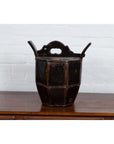 Brown wooden wedding box with carved handle, animal, and foliage motifs on polished surface by a white brick wall.