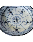 Close-up of antique Chinese blue and white ceramic footed rice bowl with floral and geometric patterns.