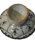 Close-up of an antique Chinese white and blue ceramic footed rice bowl upside down, showing base and blue floral design.