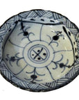 Close-up of antique Chinese white and blue ceramic footed rice bowl with blue floral motifs on the exterior.