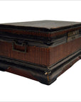 Close-up of antique Chinese wood and rattan box with dark trim, metal handles, and worn rectangular base.