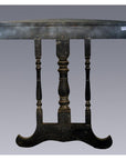 Weathered dark wood antique demi lune table with three turned legs, shown against a plain gray background.