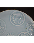 Close-up of white porcelain plate with embossed butterfly and floral patterns, antique Chinese design.