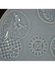 Close-up of white embossed Chinese porcelain plate with rabbit, butterfly, and floral designs.