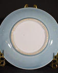 Light blue embossed Chinese porcelain plate with white center on gold stand, close-up.