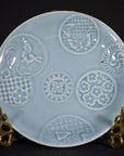 Close-up of an antique white embossed Chinese porcelain plate on a brass stand.