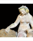Antique white stone statue of a woman with flowers in her hair, seated by a lion, draped in flowing cloth.