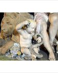 Close-up of antique European stone statue featuring a cherub with a lion, holding a snake, fruit, and lamb nearby.
