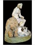 Antique white stone statue of a woman with a lion, child, and lamb on an oval base, close-up view.