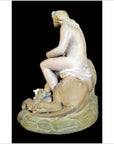 Light marble statue of a nude bearded man with long hair sitting on a rock beside a lion.