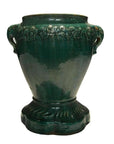 Green glazed ceramic Annamese garden seat with two handles and floral band near top, close-up view.