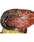 Close-up of antique hand-carved double-ram sculpture with black curved horns and detailed golden collar.