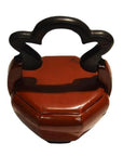 Red lacquered hand-carved Chinese wedding basket with cloud-shaped black handle on white background.
