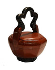 Red lacquered wood octagonal Chinese wedding basket with curved black handle, close-up on white background.
