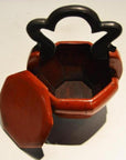 Red lacquered wood Chinese wedding basket, octagonal with black ornate handle and open matching lid, close-up view.