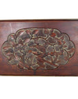 Close-up of dark red lacquered rosewood wall plaque with hand-carved central floral and leaf design.