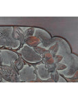 Close-up of a dark rosewood wall plaque, hand-carved and lacquered, with 19th-century Chinese floral and leaf patterns.