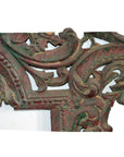Close-up of antique reddish-green wood mirror frame with hand-carved swirling leaf patterns.