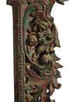 Close-up of weathered metal antique hand carved mirror frame with ornate floral and leaf designs.