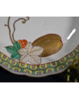 Close-up of antique hand painted Asian bowl with floral design and gold accents on a modern metal stand.