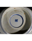 Close-up of white ceramic antique Asian bowl with blue square mark and stains in the center.