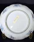White ceramic plate underside close-up with hand painted details and label reading BTR.18.15 collectible.