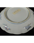 White ceramic plate underside with hand painted floral designs, label visible, close-up.