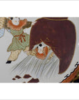 Close-up of an antique hand-painted Asian ceramic plate with two figures and a large dark red object in the center.