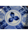 Close-up of blue and white hand painted ceramic plate with floral motif and bold abstract edge patterns.