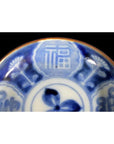 Close-up of blue and white ceramic plate with hand painted Chinese patterns and 福 (fortune) character.