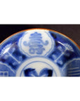 Close-up of blue and white ceramic Asian plate with hand painted decorative patterns and Chinese characters.