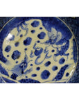 Close-up of blue and white ceramic Chinese bowl with hand painted dragon and cloud design in central circle.