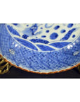 White porcelain Chinese bowl with hand painted decoration on ornate brass stand, close-up view.