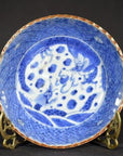 Close-up of an antique hand painted Chinese ceramic bowl with dragon and cloud motifs on a brass stand, dark background.