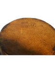 Close-up of a round brown painted antique Chinese drum surface with faint numbers and a circular stamp.