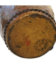 Close-up of red and brown painted ceramic drum base with stamp mark and decorative beading along edge.