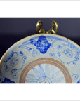 Close-up of blue and white antique hand-painted Chinese ceramic plate with faces and intricate patterns.