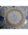 Close-up of antique hand painted porcelain plate with blue floral patterns and sun face design at center, rays around.