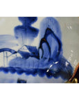 Close-up of blue and white hand painted porcelain bowl with scalloped edge, featuring Chinese landscape design.