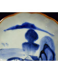 Close-up of blue and orange hand painted Chinese porcelain bowl with landscape and modern cloud motif.