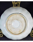 Close-up of the underside of an antique hand painted Chinese porcelain bowl on a gold stand, black background.