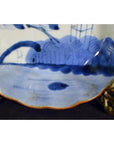 Close-up of a hand painted antique Chinese porcelain plate with colorful designs on an ornate metal stand.